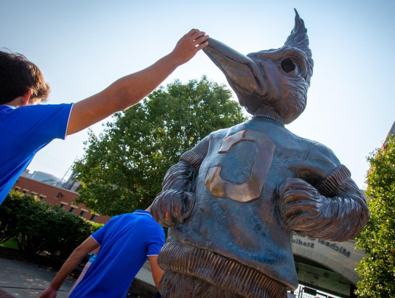 student touching Billy-Bluejay-on-Creighton-University-Campus